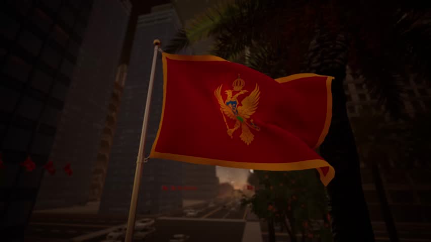 The Montenegro national flag waves gently at sunset along a modern city street, illuminated by warm golden light that reflects across surrounding buildings and urban surfaces. The contrast between the rich red of the flag and the warm tones of the sky creates a calm and visually balanced atmosphere. The golden emblem remains clearly visible, reinforcing the flag’s symbolic presence.

Urban elements such as streets, buildings, and light traffic are present without overpowering the composition, keeping the flag as the central focus. The absence of recognizable landmarks allows the image to function as a general representation of Montenegro rather than a specific location. Subtle motion in the flag adds realism while preserving a composed and professional tone.

This visual is suitable for editorial use related to international news, cultural storytelling, European affairs, or travel features. Its warm lighting and neutral composition provide flexibility for a wide range of informational and media applications.
