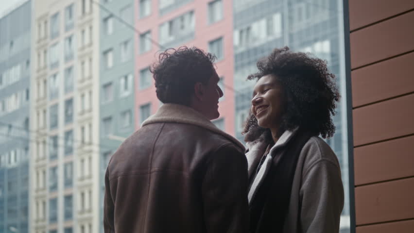 Low angle shot of biracial couple hugging and kissing goodbye after perfect date