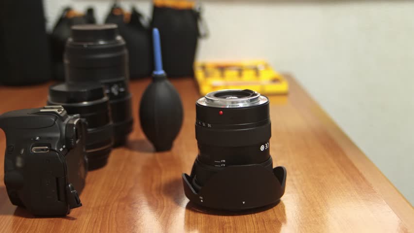 Close-up of a professional photographer adjusting the aperture and focus rings on a camera lens. Sharp detail on lens markings and mechanical movement.