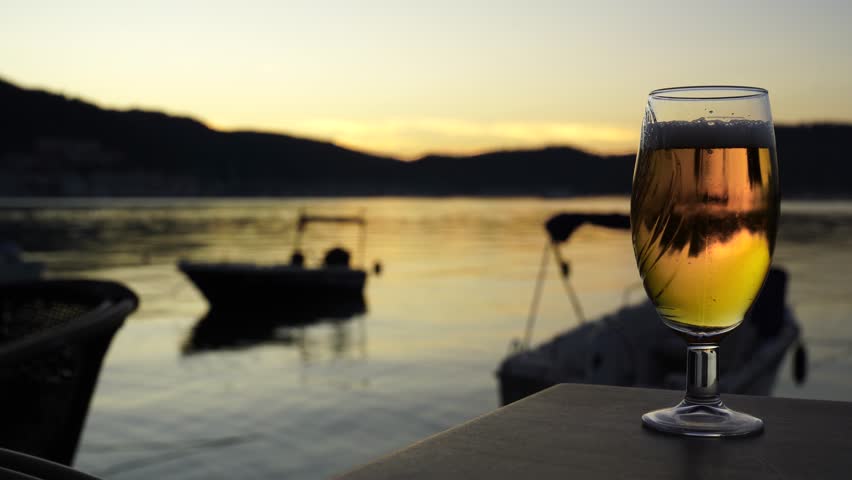 4K Pan Shot Cold Beer on Table Overlooking Sunset Sea and Boats, Fethiye