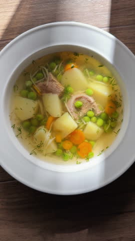 Delicious chicken noodle soup with vegetables steaming in white bowl