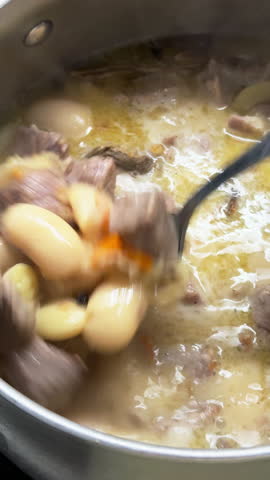 Person cooking traditional homemade pork and bean stew