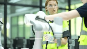 Two female engineering students programming robotic arm using tablet in modern laboratory. Young women in safety gear collaborating on industrial automation technology project at university. - Powered by Shutterstock - Get 15% off with code: PIKWIZARD15