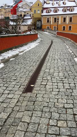 A view of buildings and pathways covered in snow under a cloudy sky during winter season in Lublin. Grodzka Gate, remains of the defensive walls. It also called the Jewish Gate. Lublin, Poland