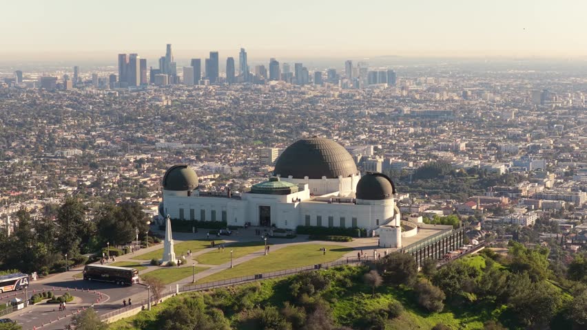Aerial drone shot of Griffith Observatory with downtown Los Angeles skyline at sunset