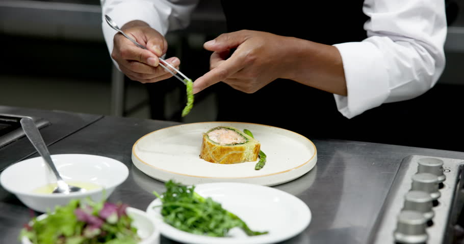 Culinary, plating or hands in restaurant with tweezers, catering or presentation in luxury cuisine. Hospitality, expert or chef in kitchen with tool, preparation or food decorating in fine dining