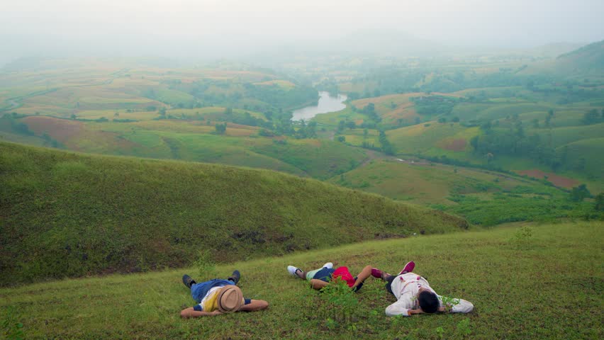 Three Man sleeping on grass with cap enjoying natural sun bath in Jagmer Hills, Surrounded by Lush Greenery near Udaipur, Banswara, Rajasthan, India.