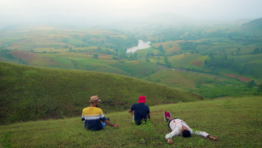 Three Man sleeping on grass with cap enjoying natural sun bath in Jagmer Hills, Surrounded by Lush Greenery near Udaipur, Banswara, Rajasthan, India.