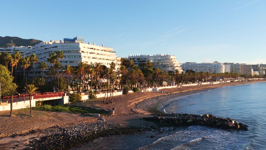 Golden Dawn in Marbella: Stunning Aerial Sunrise View of Luxury Resorts, the Coastal Promenade, and Pristine Mediterranean Beaches on the Costa del Sol
