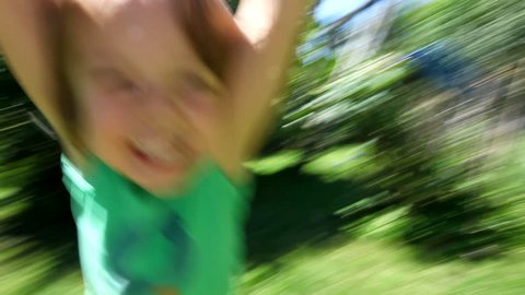 Little boy spinning around and around laughing and smiling at the end of his fathers arms on a sunny day