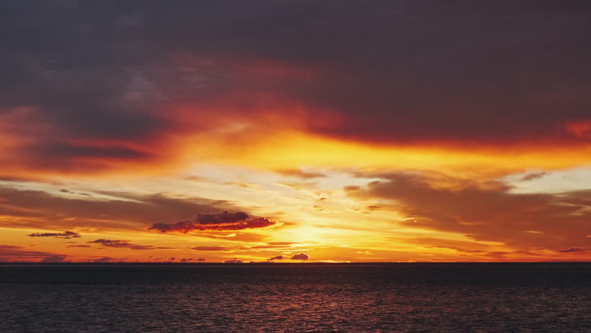 Landscape after sunset with vibrant red and orange sky reflecting on water and shore. Beautiful seascape, 4k