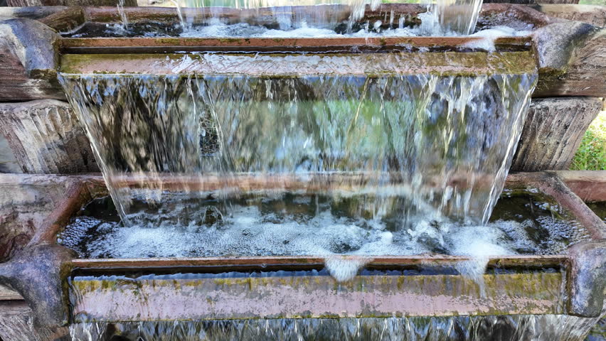 Tranquil Garden Oasis Water Cascades Over Stone Tiers in Rustic Fountain, Creating Peaceful Ambiance with Natures Beauty and Soothing Sounds of Outdoor Serenity