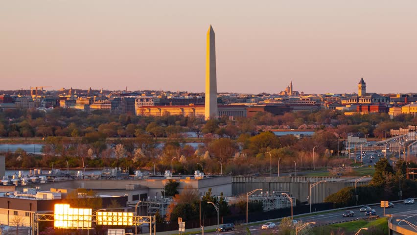 Washiongton DC. Aerial view of Washington Monument during sunset, with cityscape in the background. The Washington Monument stands tall against a pinkishpurple sky.