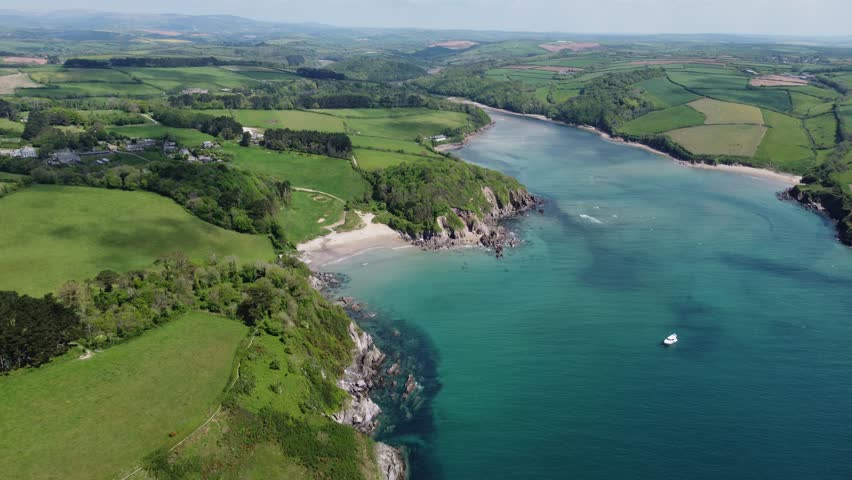 Aerial drone footage of the Mothecombe estuary on the River Erme in South Devon, England, showing winding tidal waters, sandbanks, and surrounding rural countryside. Calm, scenic coastal landscape captured on a clear day, ideal for travel, nature, environmental, and UK location visuals.
