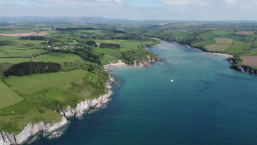 Aerial drone footage of the Mothecombe estuary on the River Erme in South Devon, England, showing winding tidal waters, sandbanks, and surrounding rural countryside. Calm, scenic coastal landscape captured on a clear day, ideal for travel, nature, environmental, and UK location visuals.