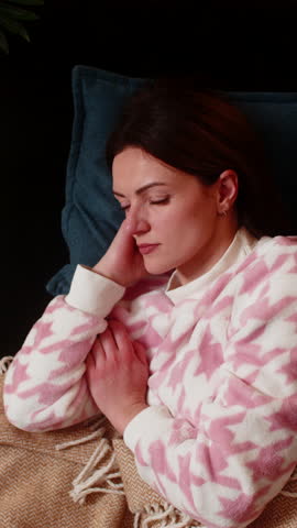 Adult woman lies awake at night home tries to sleep feels restless anxious breath slow eyes closed. Caucasian girl on sofa at evening shows insomnia signs frowns sighs turns on side seeks calm rest