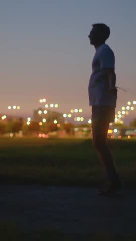 Person calmly gazes at city horizon during twilight, Individual contemplating cityscape amidst tranquil dusk atmosphere, Person peacefully surveys glowing skyline as day ends peacefully
