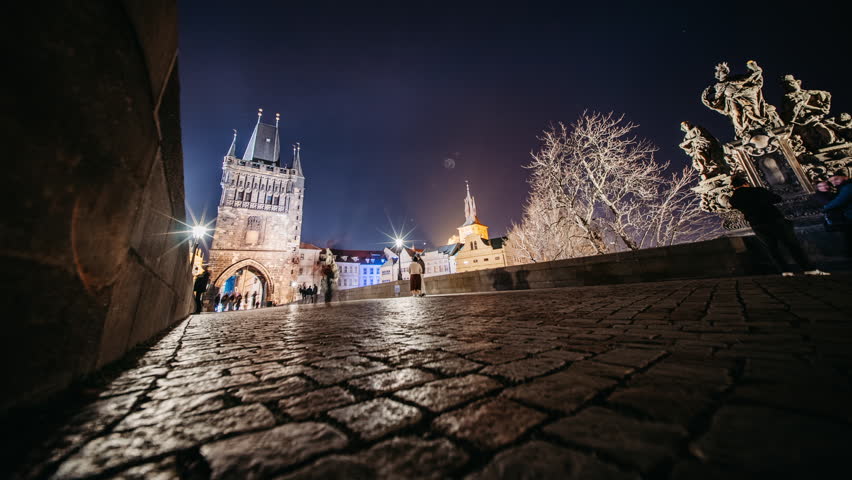 Night Timelapse of Crowds and City Life on Iconic Charles Bridge, Prague. People, street performers, illuminated historic sculptures, lively nightlife and tourism.