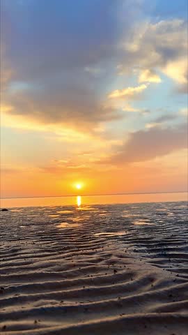 Timelapse sunset over sandy beach and calm sea
Vertical timelapse video of a peaceful sunset over a sandy beach with gentle sea waves and soft clouds moving across the sky. Warm golden light reflects on the horizon, creating a calm and relaxing coastal atmosphere. Ideal for nature backgrounds, travel visuals, meditation content, mobile wallpapers, social media stories, reels, and cinematic seaside projects. No people.