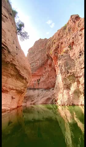 Boat floating through narrow canyon with green water
Vertical video of a small boat moving through a narrow rocky canyon with calm green water. Natural landscape scene with dramatic canyon walls, suitable for Instagram Reels, TikTok videos, social media stories, mobile backgrounds, travel visuals, and nature content. No people.