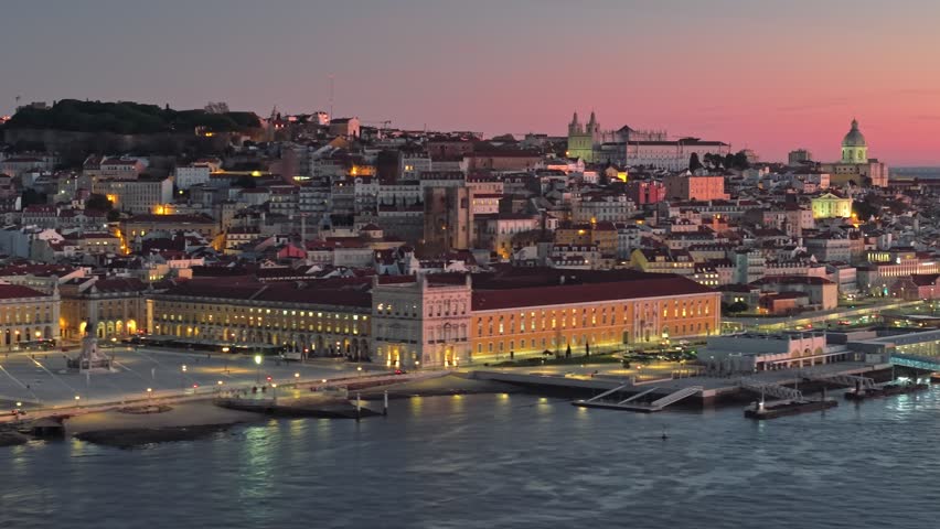 Aerial shot of Lisbon city center at sunrise. Morning lights illuminate the city of Lisbon along the river, Portugal 