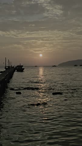 Video of a sunset view on the beach with a wooden pier in the background