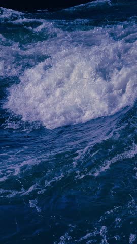 Slow motion cinematic 4K B roll footage of a dramatic ocean wave breaking vertically with massive white foam and spray against deep blue water. This faceless B roll features clean composition and minimalist style under natural lighting, creating a joyful atmosphere with positive vibes and modern lifestyle energy. High-resolution cinematic footage offers ample copy space and text space, perfect as background footage for advertising, marketing, branding, social media, websites, presentations, corporate projects, and creative visual content. Smooth visual flow, turbulent foam textures, and golden hour warmth deliver viral trend appeal for digital media, commercial backgrounds, and storytelling visuals.