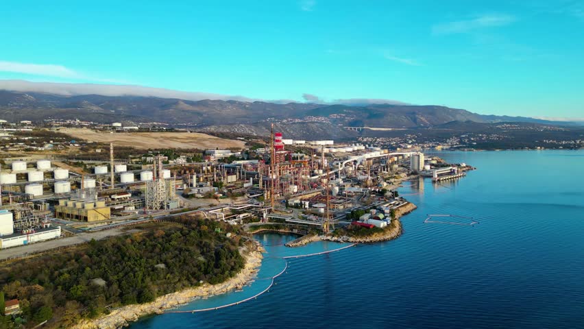 Aerial view of the INA Rijeka Refinery at Urinj, Croatia, nestled along the Adriatic coast with mountains in the background. A blend of industrial might and natural beauty.