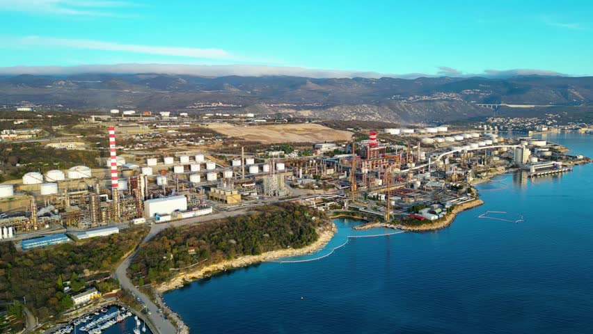 Aerial view of the INA Rijeka Refinery at Urinj, Croatia, nestled along the Adriatic coast with mountains in the background. A blend of industrial might and natural beauty.