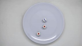 a person's hand reaches into the frame to collect the dice from the plate and shakes them using the hand and throws them onto the white plate until they become triple one pips - Powered by Shutterstock - Get 15% off with code: PIKWIZARD15