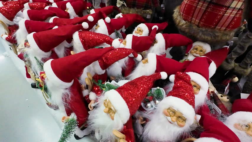 Close-up shot of many Santa Claus toys on display in a shopping center. Festive Christmas decorations for sale in a retail store. Holiday season shopping for traditional Santa figures.