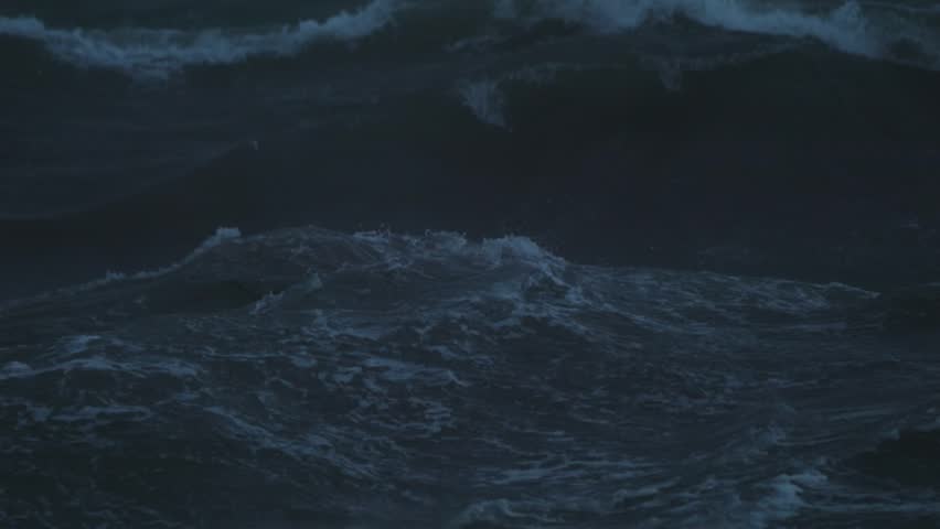 Slow motion view of agitated sea waves filmed in the evening light after sunset with strong wind and stormy conditions.