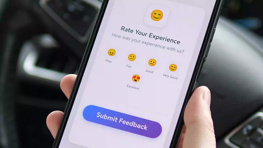 This closeup shows a driver contemplating a simple yet expressive 5 emoji feedback scale on their phone, representing the universal act of rating an experience. Perfect for any content involving