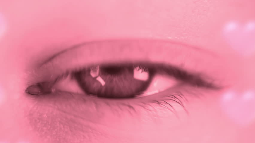 Female eye close-up. Toning in pink. Many shapes of heart fly with every blink