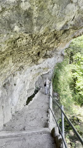 Narrow mountain path carved into rock with metal railing, hiking trail along cliff, adventure route, natural passageway, outdoor exploration
