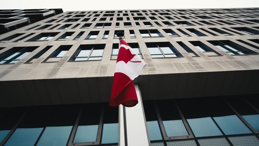 Maple Leaf Flag Of Canada Fluttering On A Pole In The City