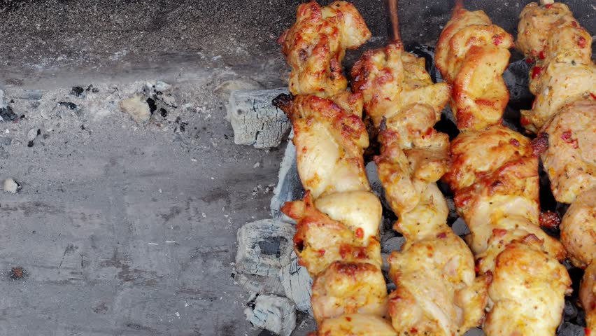 Charred meat on open fire, Blackened chicken sticks cooking on rustic outdoor grill, Burst of smoky aroma from seared chicken skewers on natural outdoor fire source