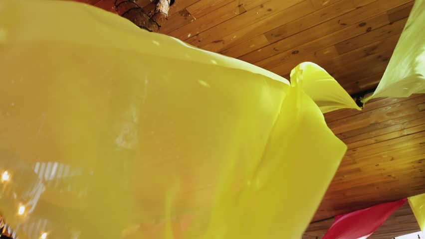 Bright yellow fabric hanging from a wooden ceiling. Design, wedding, decoration for an event or party.