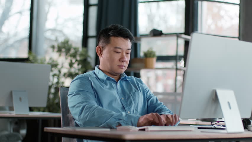 Focused Man Working at Modern Office Desk in Bright Environment During Daytime Hours