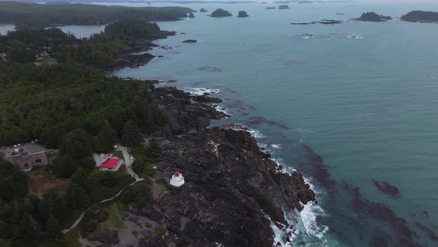 Drone flying high above lighthouse on rocky coast of Ucluelet, Vancouver Island in cloudy foggy weather. Filmed August 02 2025