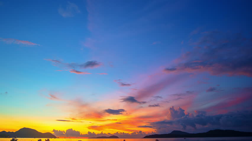time lapse A stunning seascape capturing the vibrant colors of a dramatic sunset sky over a calm beach, with soft waves and silhouetted clouds adding depth and serenity to the scene.