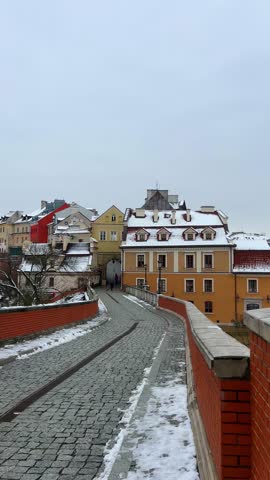 A view of buildings and pathways covered in snow under a cloudy sky during winter season in Lublin. Grodzka Gate, remains of the defensive walls. It also called the Jewish Gate. Lublin, Poland