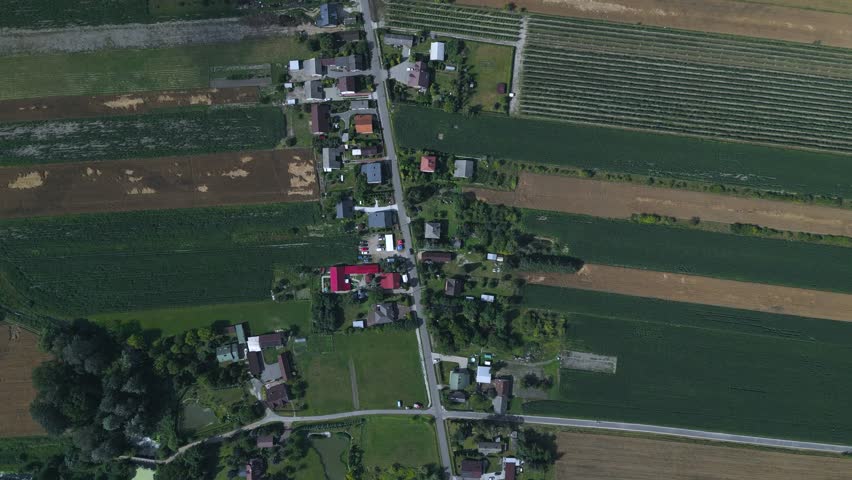 High-altitude vertical drone footage of a traditional Polish ribbon village, showcasing the unique geometric patterns of narrow agricultural strips and residential properties in Mysłaków.