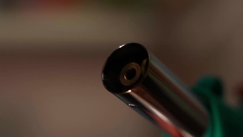 Ignition of butane torch close-up on blurred background
