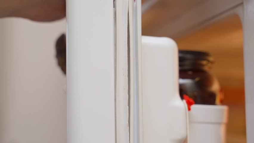Hand showing torn rubber band on refrigerator door, close-up
