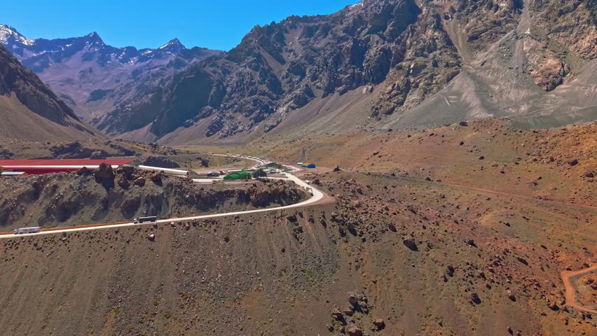 Aerial view of the Portillo Mountains on the Chilean-Argentine border on a sunny day with a long line of loaded buses waiting to enter Chile.