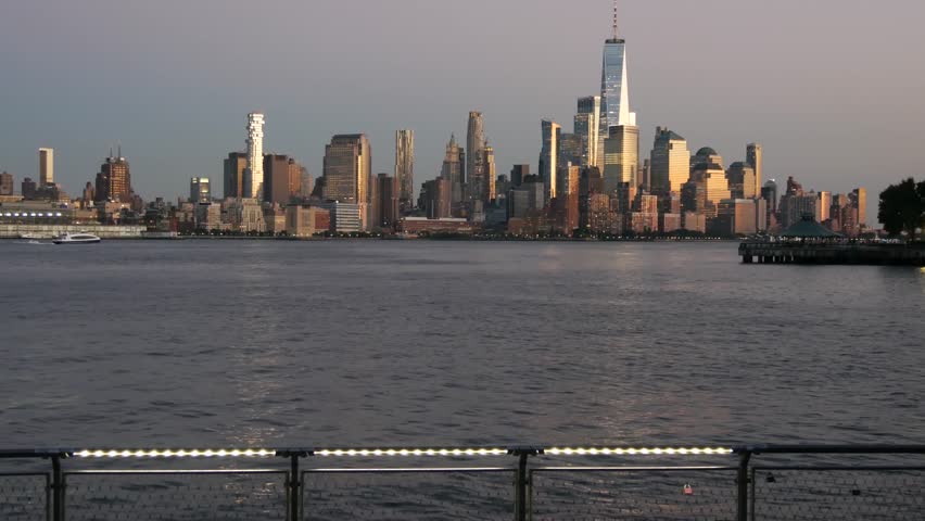 New York City Manhattan Downtown Financial District skyline, World Trade Center tower skyscraper from New Jersey, Hoboken pier, United States. River waterfront urban cityscape, evening dusk twilight.