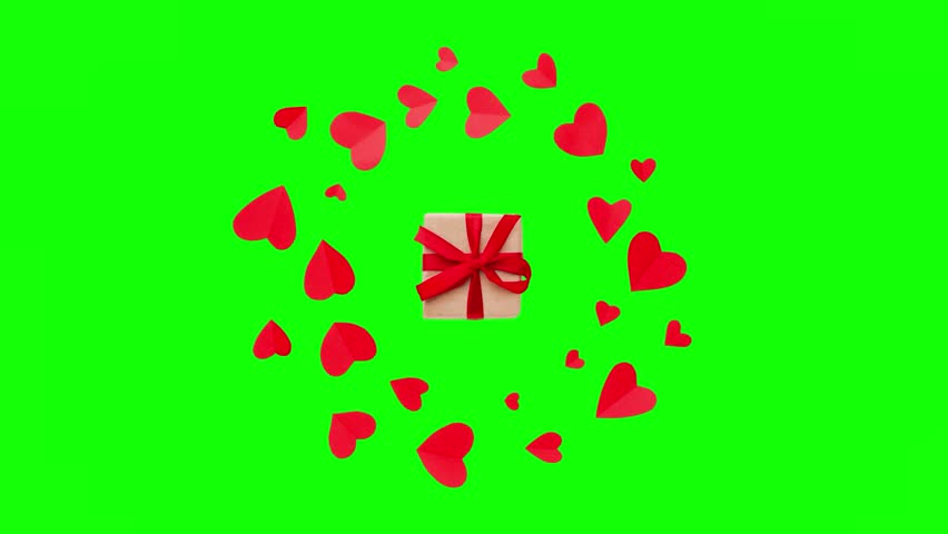 Small red paper hearts floating in a circular motion around a brown gift box tied with a red ribbon on a green screen background for chroma key editing.