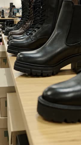 Black leather boots on wooden shelf in shoe boutique. Classic men