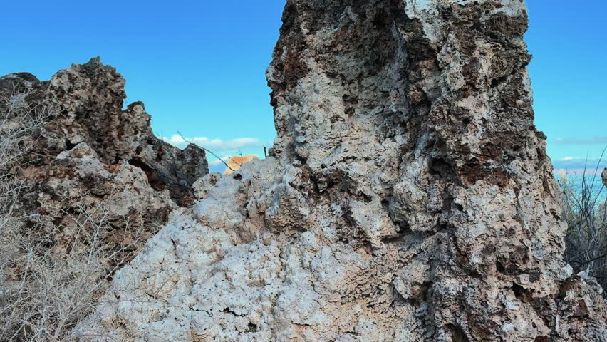 Ascending close up aerial of the Eastern Sierra landscape in Mono County, California, USA, featuring the Mono Lake Tufa Pinnacles and the rugged Sierra Nevada peaks along Highway 395.